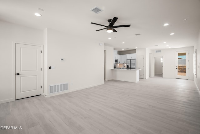 unfurnished living room with light hardwood / wood-style flooring, sink, and ceiling fan