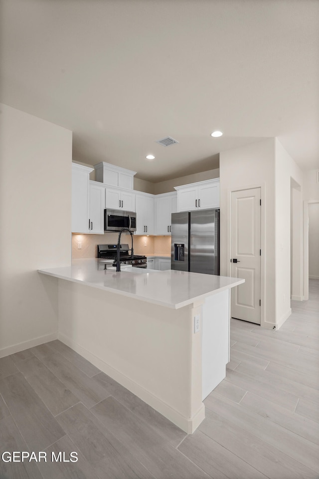 kitchen featuring appliances with stainless steel finishes, white cabinetry, and light hardwood / wood-style floors