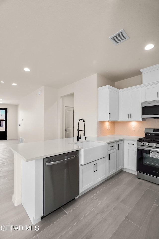 13870 Paseo Central Ave, Horizon City, TX 79928 - kitchen with stainless steel appliances, a sink, light countertops, recessed lighting, and white cabinetry