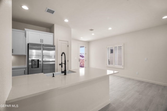 kitchen featuring sink, white cabinets, stainless steel refrigerator with ice dispenser, and light hardwood / wood-style flooring