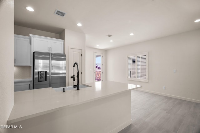 13870 Paseo Central Ave, Horizon City, TX 79928 - kitchen with stainless steel fridge, white cabinetry, light wood-style floors, recessed lighting, and light countertops