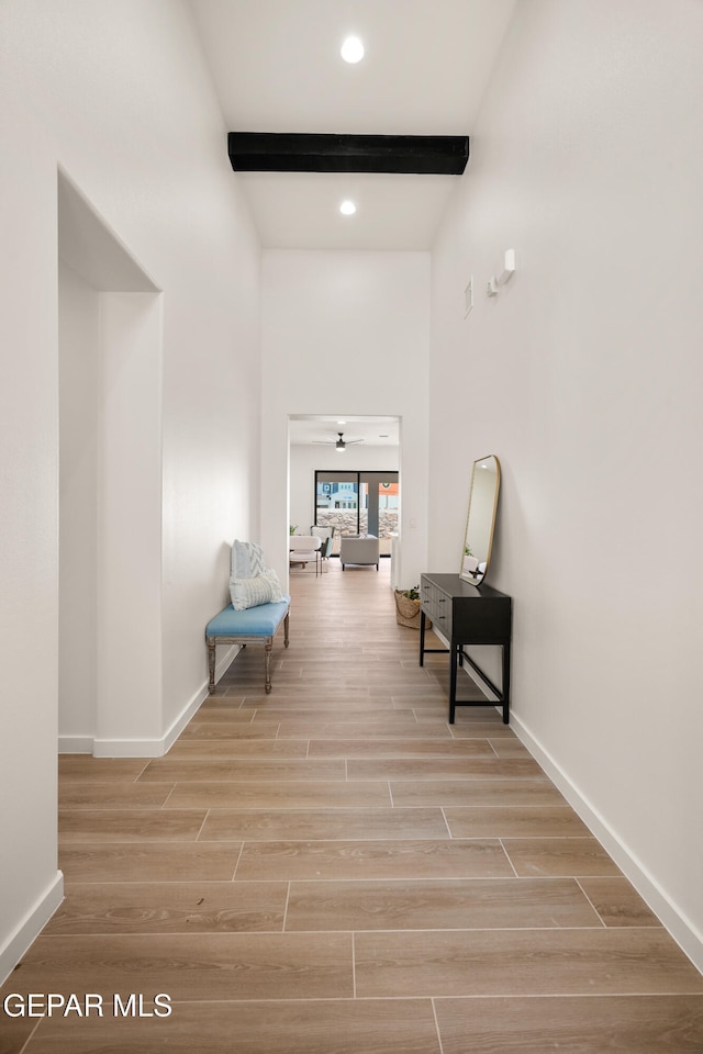 corridor with beam ceiling and light hardwood / wood-style floors