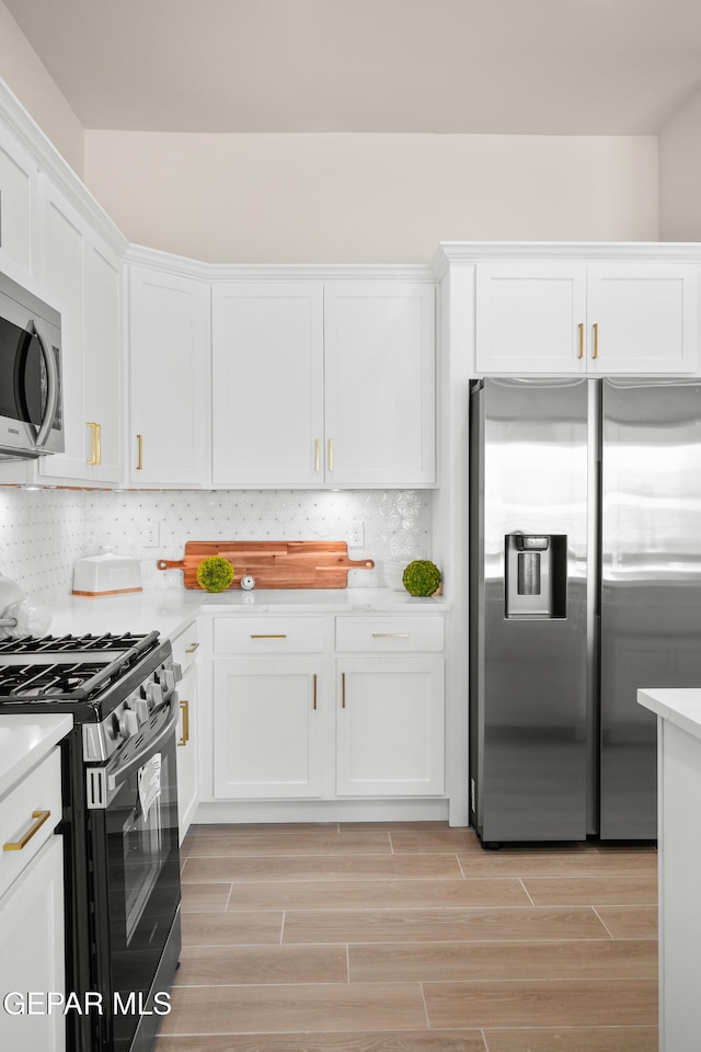 kitchen featuring appliances with stainless steel finishes, white cabinets, backsplash, and light hardwood / wood-style floors