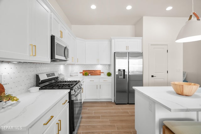 kitchen with white cabinets, a breakfast bar, light wood-type flooring, pendant lighting, and stainless steel appliances