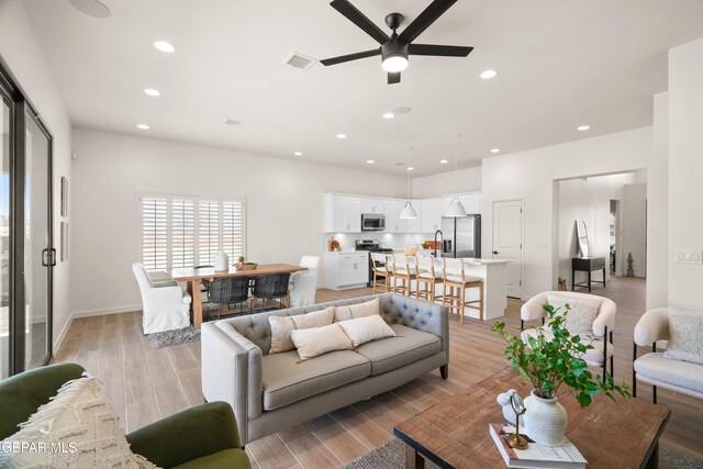 living room featuring light hardwood / wood-style flooring and ceiling fan