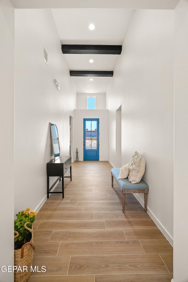 hallway featuring beamed ceiling and light wood-type flooring