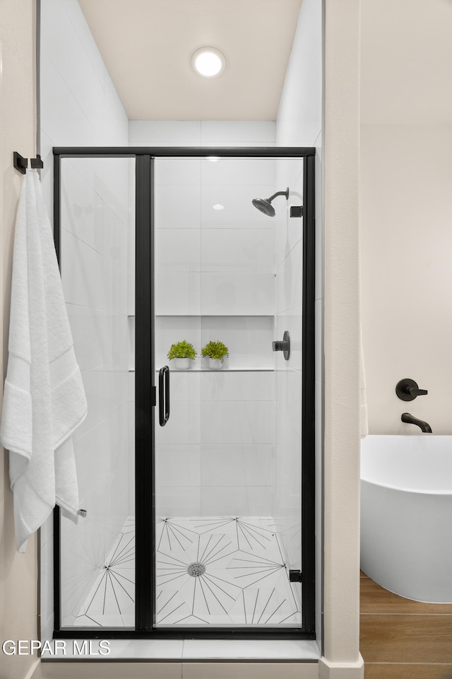 bathroom with shower with separate bathtub and hardwood / wood-style floors