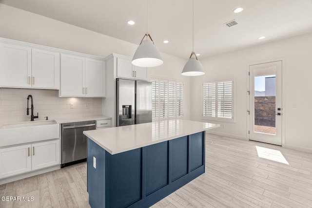 kitchen with a kitchen island, white cabinetry, pendant lighting, light hardwood / wood-style floors, and stainless steel appliances