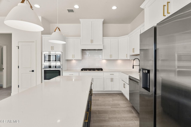 kitchen featuring light hardwood / wood-style flooring, decorative light fixtures, white cabinets, and stainless steel appliances