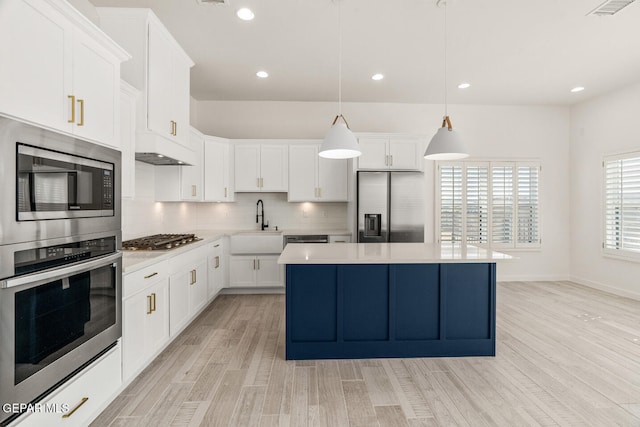 kitchen featuring sink, pendant lighting, white cabinetry, appliances with stainless steel finishes, and light hardwood / wood-style floors