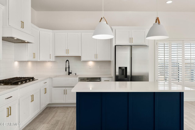 kitchen with white cabinetry, appliances with stainless steel finishes, decorative light fixtures, and light wood-type flooring