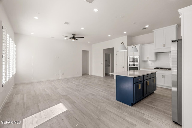 kitchen with a kitchen island, ceiling fan, light hardwood / wood-style floors, pendant lighting, and white cabinets