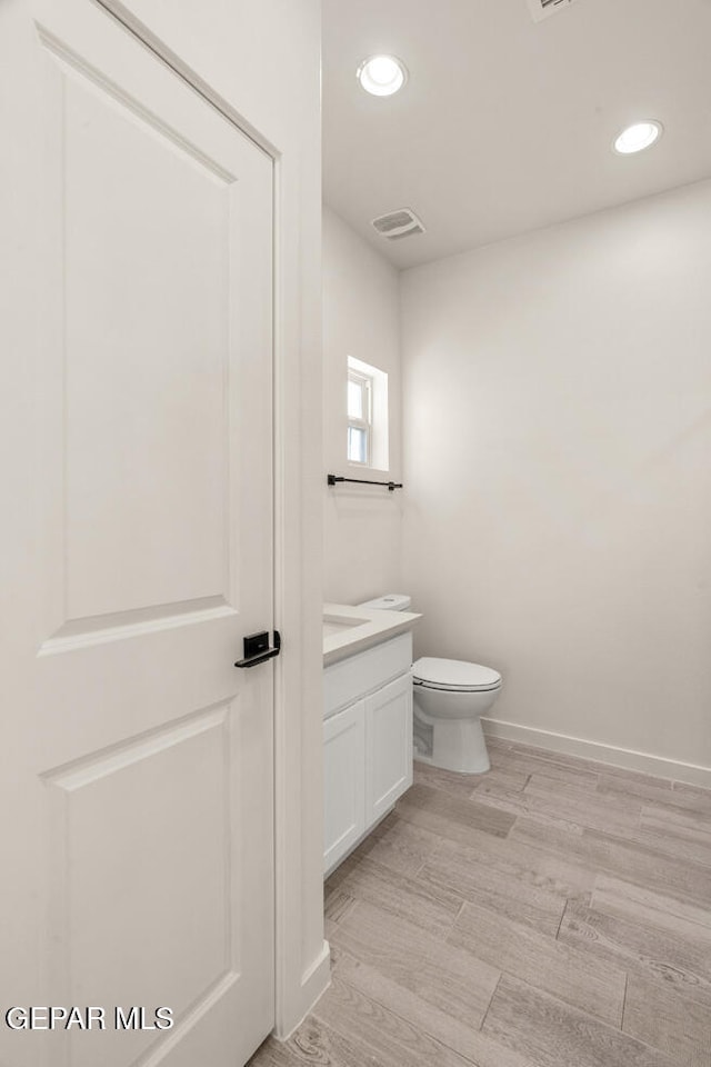 bathroom featuring vanity, hardwood / wood-style floors, and toilet