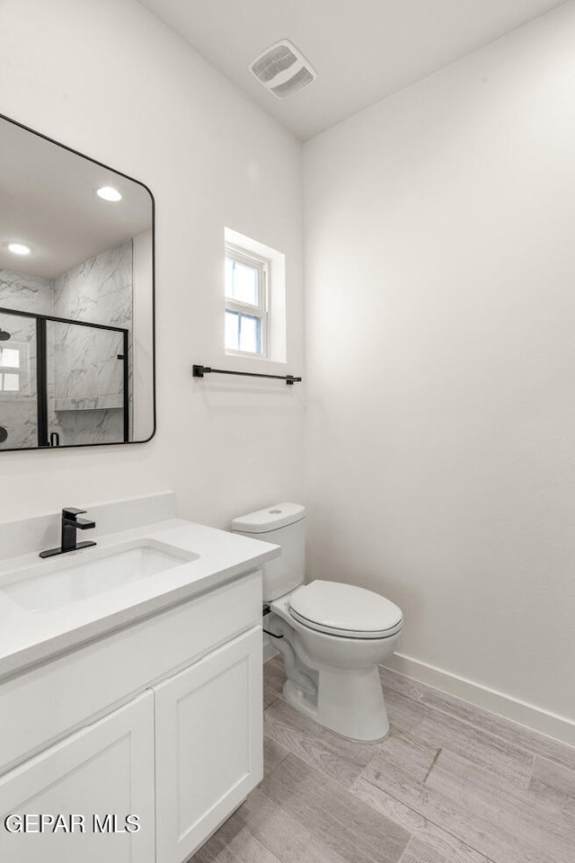 bathroom with vanity, a shower with shower door, wood-type flooring, and toilet