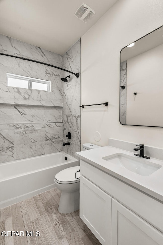 full bathroom with vanity, toilet, tiled shower / bath combo, and hardwood / wood-style floors