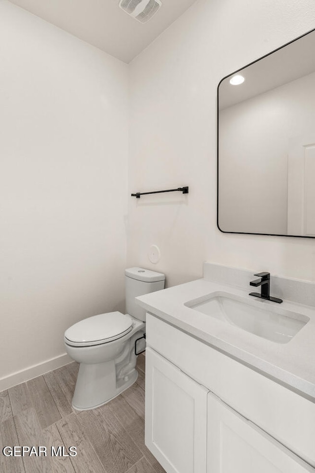 bathroom featuring vanity, hardwood / wood-style floors, and toilet