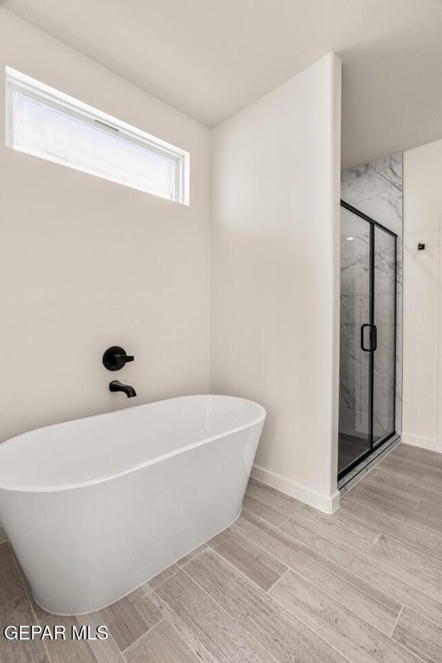 14960 Hill Ridge Ct, El Paso, TX 79938 - bathroom with a freestanding tub, a stall shower, wood finished floors, and baseboards