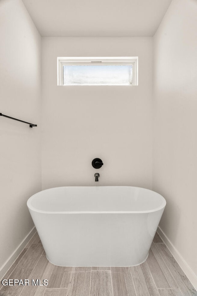 bathroom featuring a healthy amount of sunlight, hardwood / wood-style flooring, and a bathtub