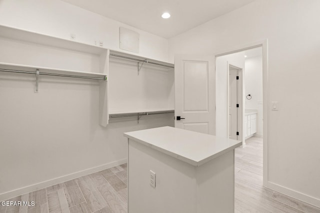 walk in closet with light hardwood / wood-style floors