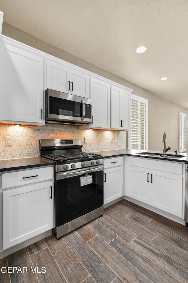 kitchen with a wealth of natural light, sink, appliances with stainless steel finishes, and dark wood-type flooring