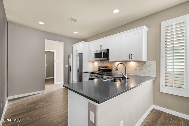 kitchen featuring appliances with stainless steel finishes, kitchen peninsula, white cabinetry, and dark wood-type flooring