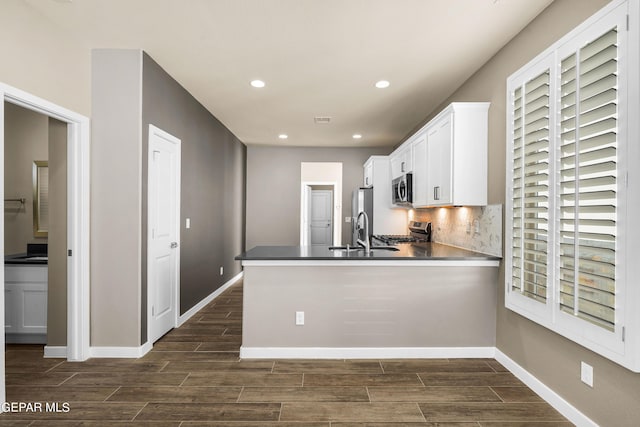 kitchen with appliances with stainless steel finishes, sink, white cabinets, and kitchen peninsula