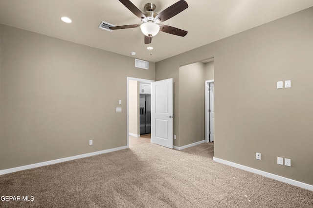 unfurnished bedroom featuring stainless steel fridge with ice dispenser, light colored carpet, and ceiling fan