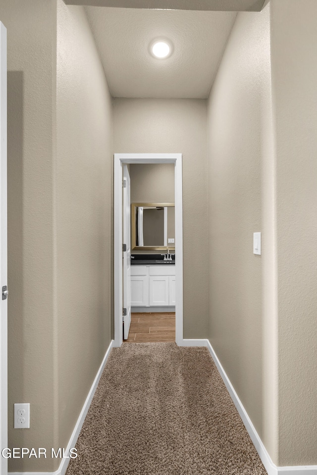 corridor featuring a textured ceiling and light colored carpet