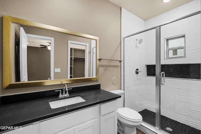 bathroom with vanity, toilet, a shower with shower door, and ceiling fan