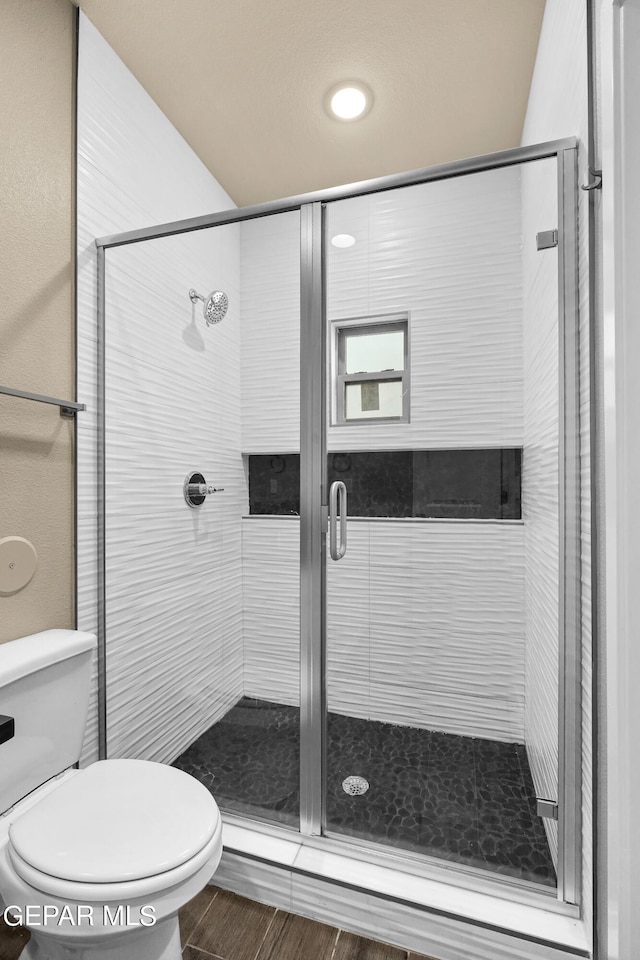 bathroom featuring toilet, hardwood / wood-style flooring, and a shower with shower door