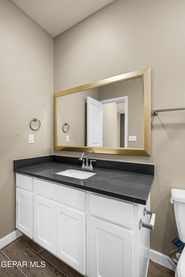 bathroom with toilet, vanity, and wood-type flooring