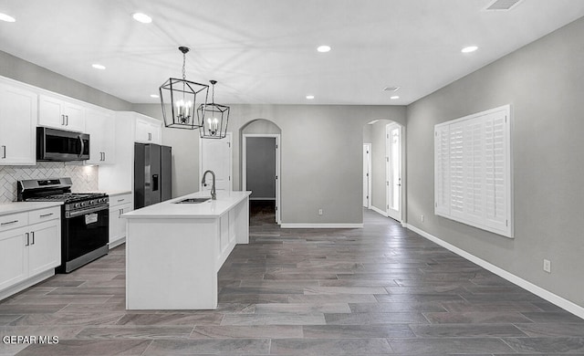 kitchen with appliances with stainless steel finishes, sink, an island with sink, pendant lighting, and white cabinets