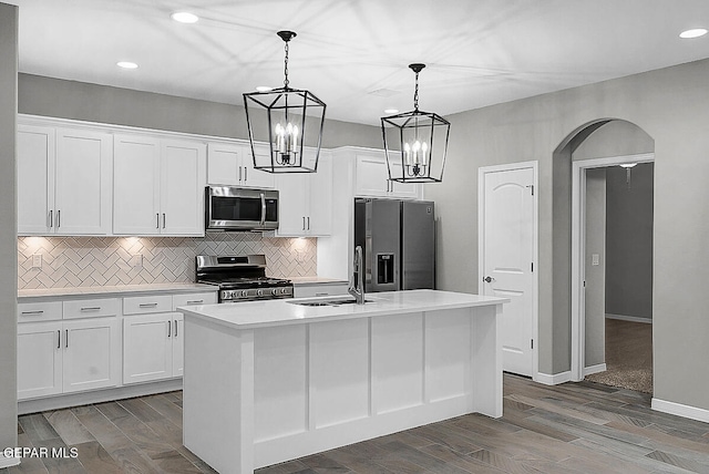 kitchen with white cabinetry, stainless steel appliances, sink, and a kitchen island with sink