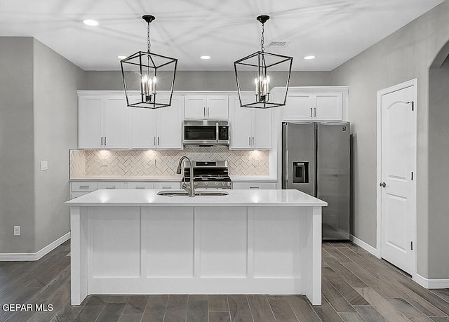 kitchen featuring a center island with sink, white cabinets, decorative light fixtures, and stainless steel appliances