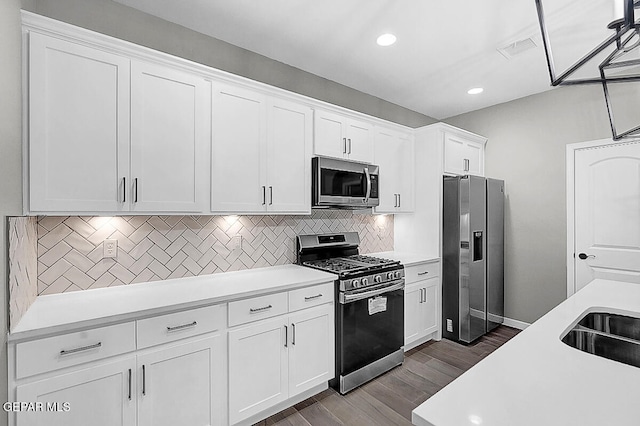 kitchen with stainless steel appliances, backsplash, sink, hardwood / wood-style floors, and white cabinets