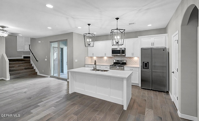 kitchen with a kitchen island with sink, sink, white cabinets, appliances with stainless steel finishes, and dark hardwood / wood-style flooring