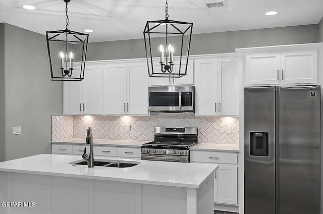 kitchen with appliances with stainless steel finishes, white cabinets, decorative light fixtures, and sink