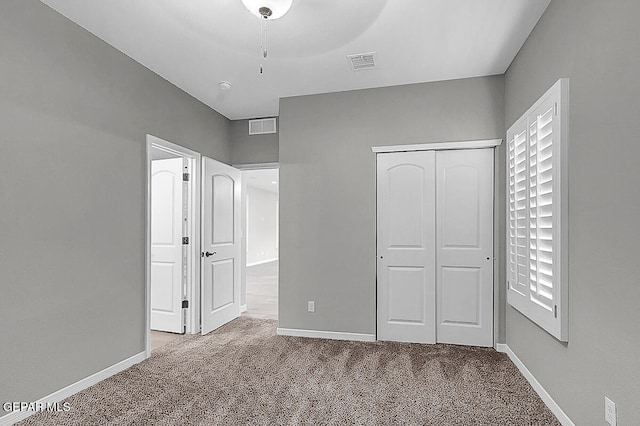 unfurnished bedroom featuring carpet floors, a closet, and ceiling fan