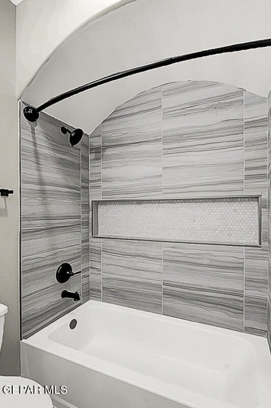 bathroom featuring tiled shower / bath combo and toilet