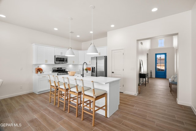 14956 Hill Ridge Ct, El Paso, TX 79938 - kitchen featuring appliances with stainless steel finishes, an island with sink, a breakfast bar area, light wood-type flooring, and recessed lighting