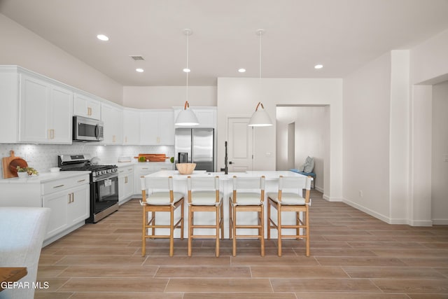 14956 Hill Ridge Ct, El Paso, TX 79938 - kitchen with appliances with stainless steel finishes, a kitchen breakfast bar, light wood finished floors, white cabinets, and recessed lighting