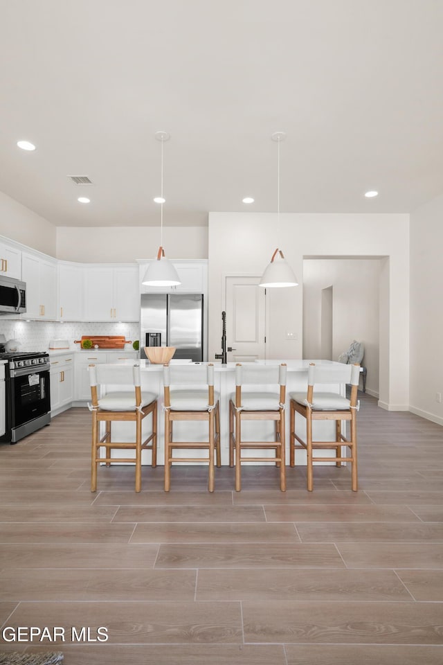 14956 Hill Ridge Ct, El Paso, TX 79938 - kitchen featuring appliances with stainless steel finishes, light wood-style floors, a kitchen breakfast bar, recessed lighting, and white cabinets