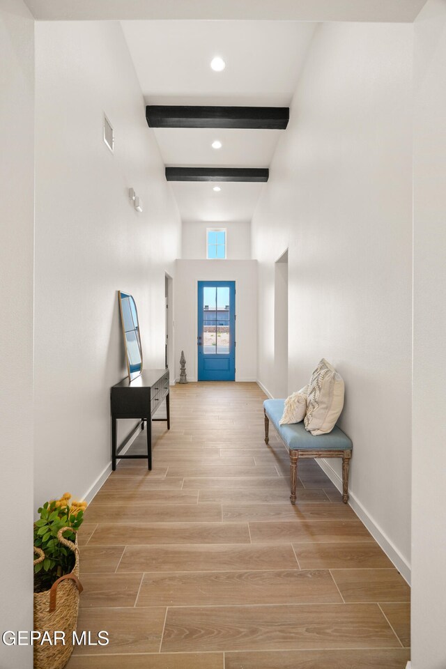 hallway with beam ceiling and light wood-type flooring