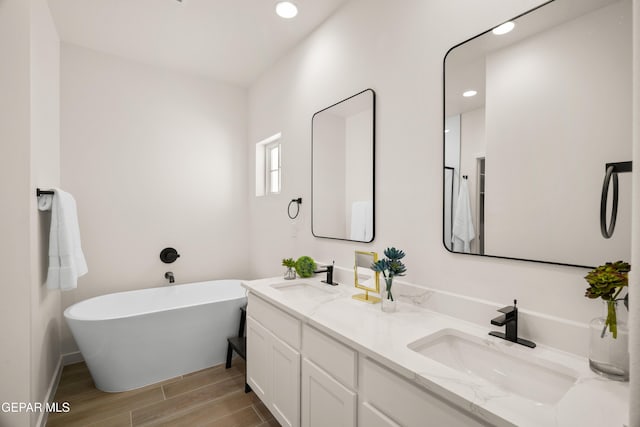 14956 Hill Ridge Ct, El Paso, TX 79938 - bathroom featuring double vanity, wood finished floors, a freestanding bath, recessed lighting, and baseboards