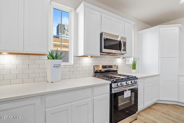 14952 Hill Ridge Ct, El Paso, TX 79938 - kitchen featuring appliances with stainless steel finishes, white cabinets, light countertops, light wood-style flooring, and backsplash