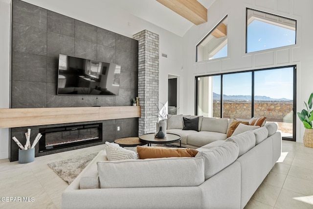 living room featuring a tile fireplace, a wealth of natural light, light tile patterned floors, and a high ceiling