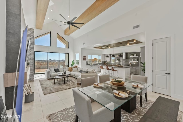 dining room with ceiling fan, light tile patterned flooring, a towering ceiling, and beam ceiling