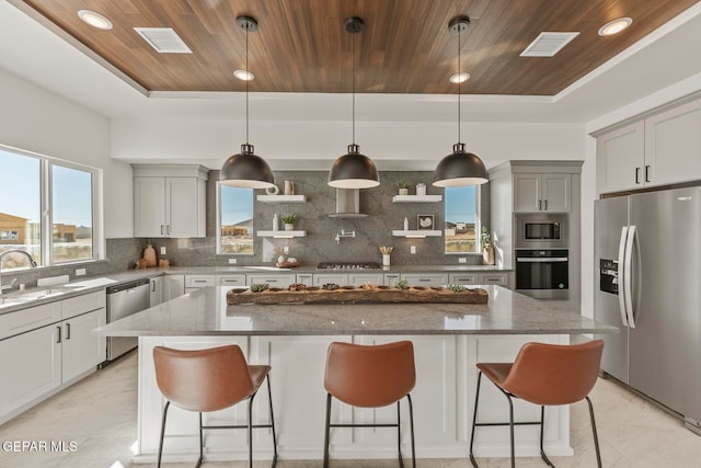 kitchen with backsplash, wood ceiling, stainless steel appliances, sink, and a kitchen island