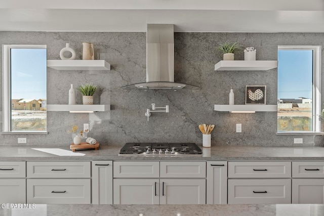 kitchen with white cabinets, wall chimney exhaust hood, backsplash, and stainless steel gas cooktop