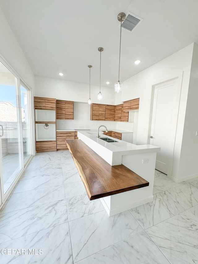 1783 Urijah Pl, El Paso, TX 79928 - kitchen with brown cabinetry, a sink, light marble finish floors, modern cabinets, and recessed lighting